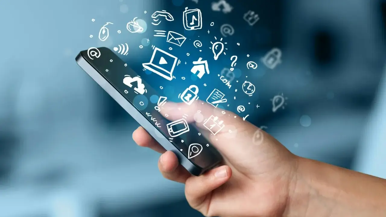 En hand håller en smartphone med en virvel av ikoner som representerar roliga appar och digitala tjänster.