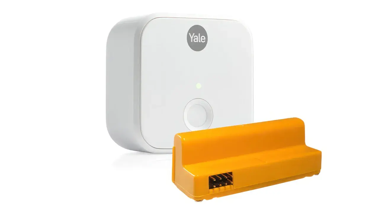Vit Yale Doorman-enhet och en orange adapter med kontakter. Perfekt för att byta kod på din Yale Doorman.
