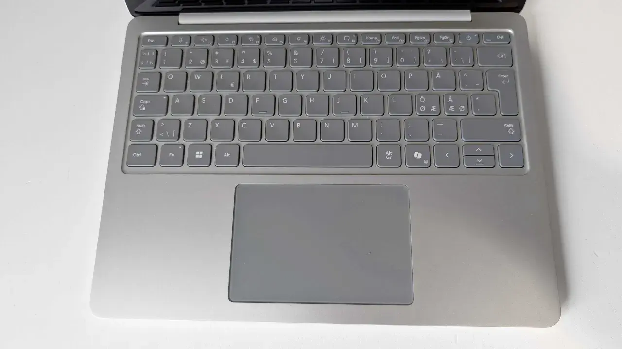 Grå laptop med tangentbord och styrplatta. Tangenterna har svenska tecken, inklusive å, ä, ö. Ett tankstreck syns på tangentbordet.