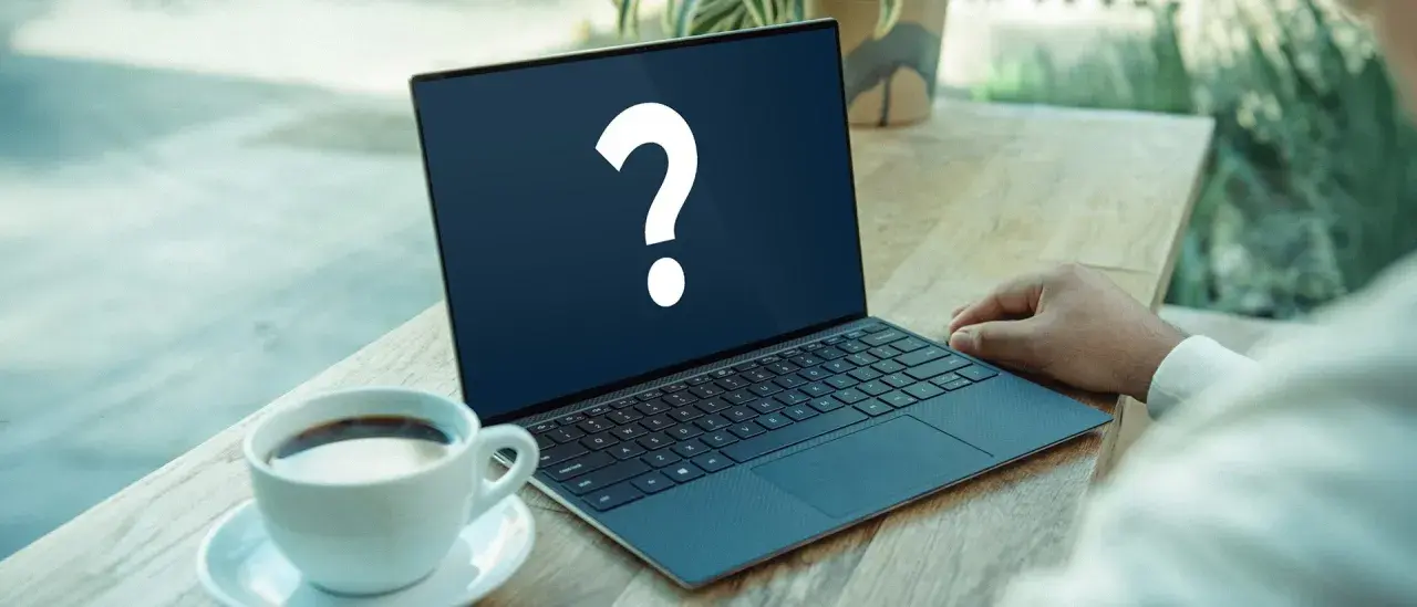 En bärbar dator med ett stort frågetecken på skärmen, bredvid en kaffekopp. Kanske letar du efter ett operativsystem gratis?