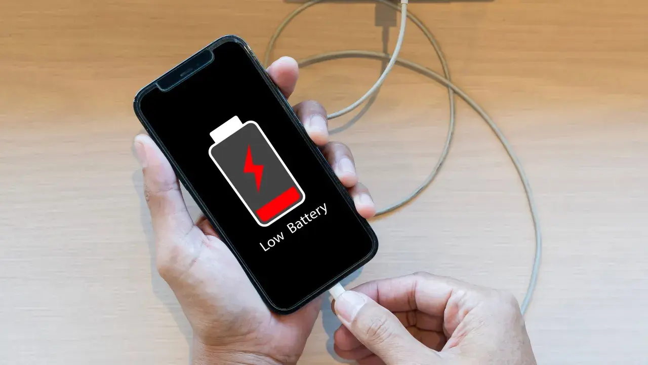 En person försöker ladda sin mobil, men den laddar inte. Batteriikonen visar låg nivå.