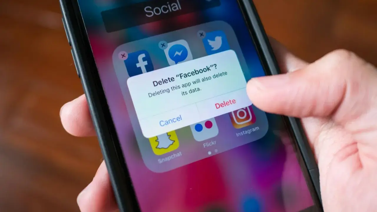 En finger trycker på "Delete" på en iPhone. En ruta frågar om man vill radera Facebook och dess data. Detta är inte hur man uppdaterar en app.