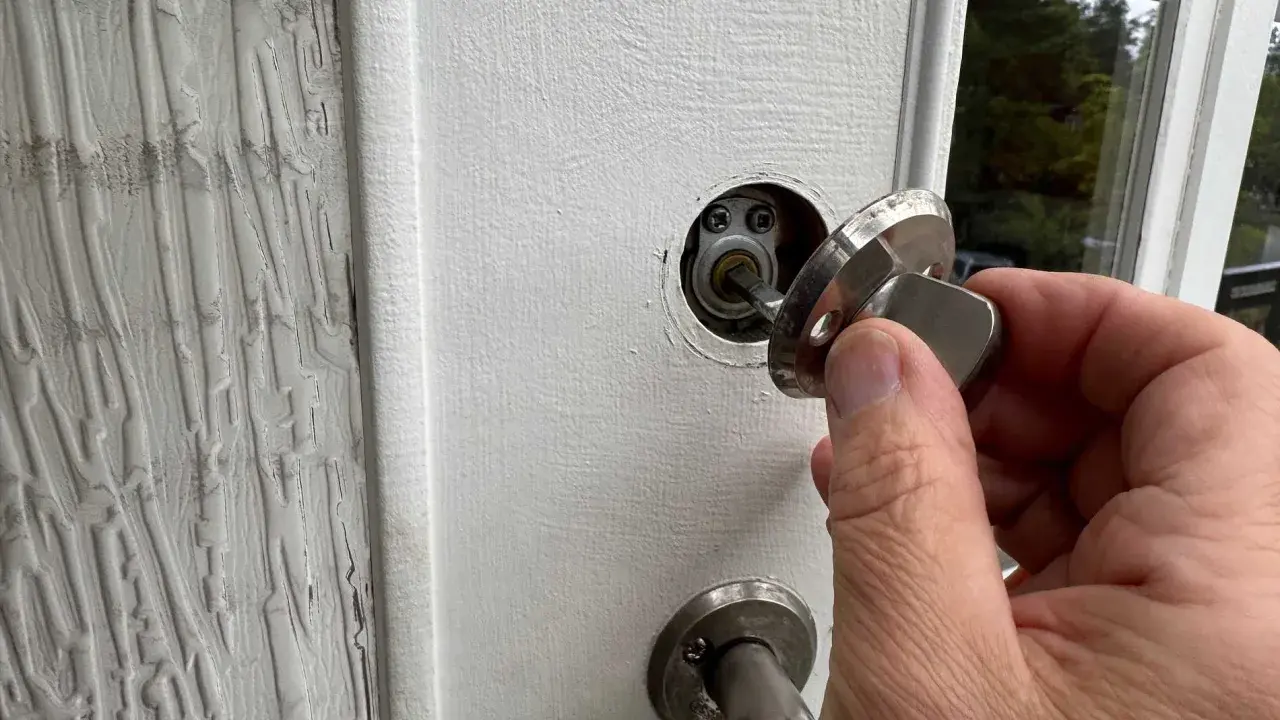 En hand håller en nyckel till en vit dörr, redo att aktivera den smarta låsmodulen.