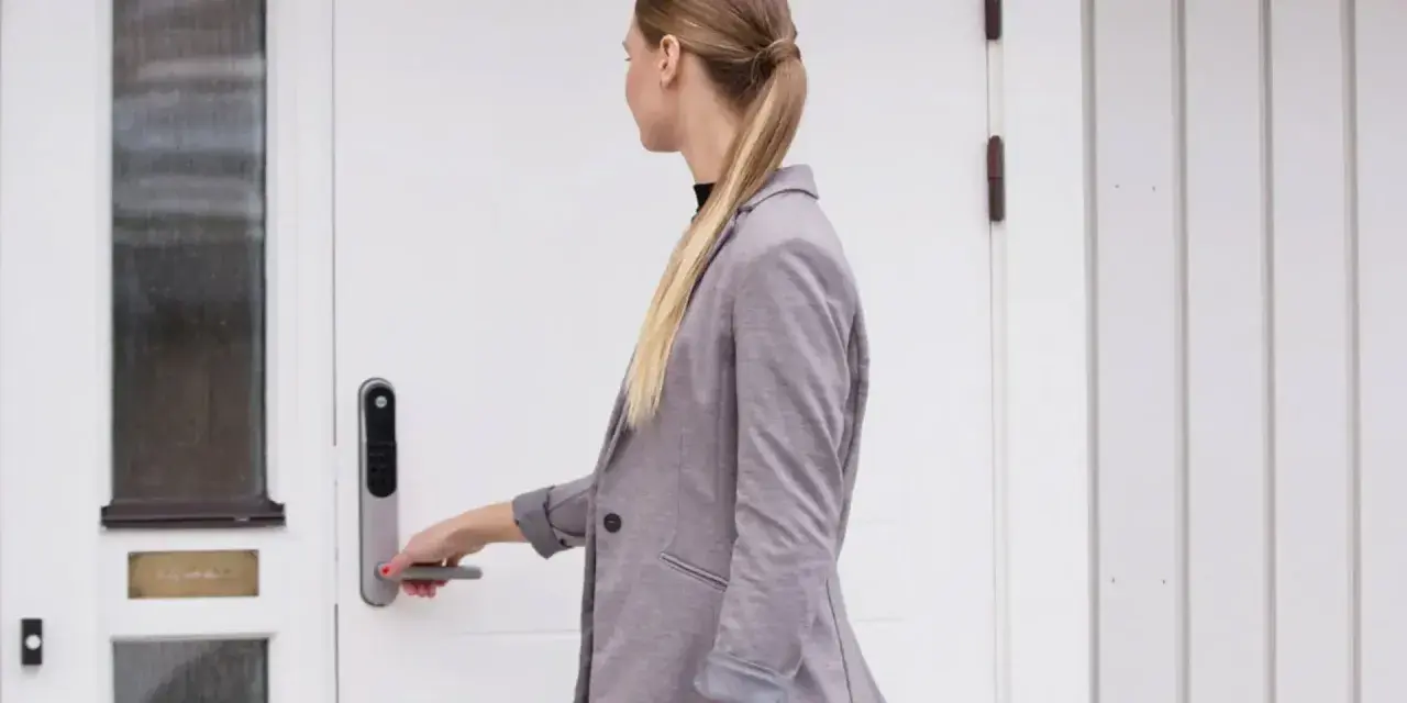 Kvinna med hästsvans öppnar en vit, gammal dörr med en Yale Doorman.