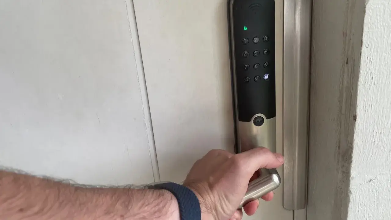 Hand griper handtaget på ett Yale v3 dörrlås med digital knappsats.