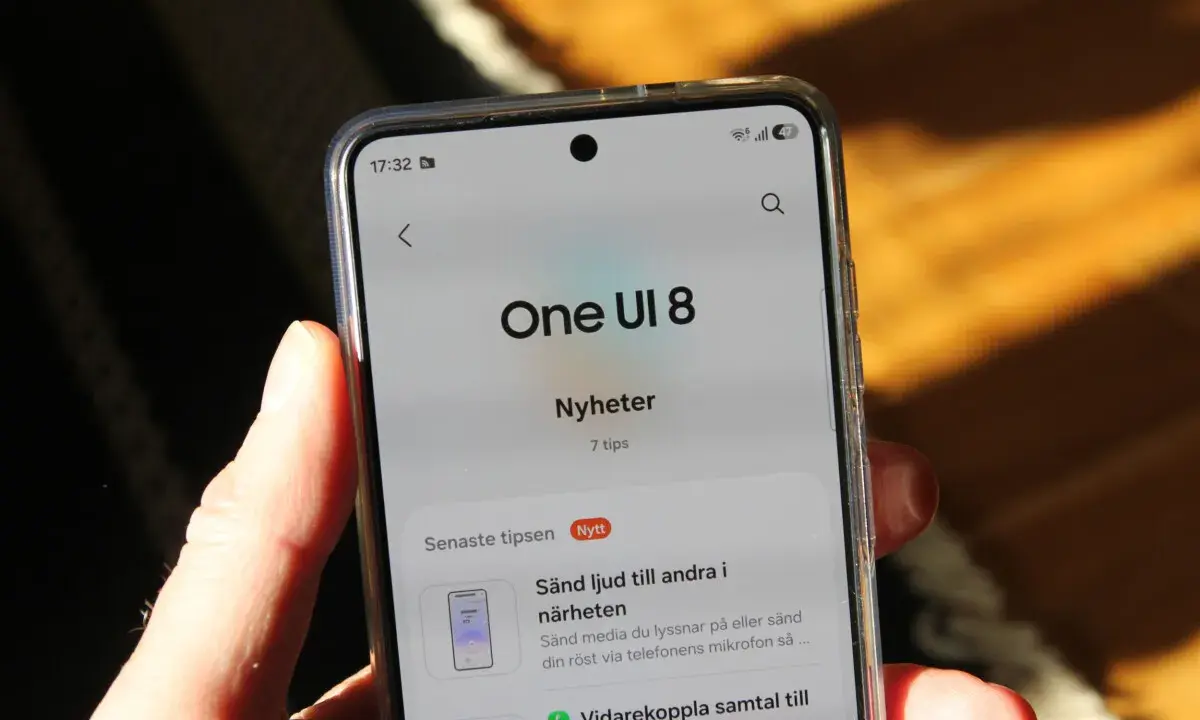 En hand håller en telefon som visar "One UI 8 Nyheter" med tips om funktioner.
