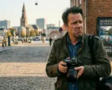 Fotograf med kamera funderar på AI:s roll i att fixa bilder. Stadsbild i bakgrunden.