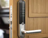En modern Yale doorman med digitalt tangentbord och handtag på en träport.