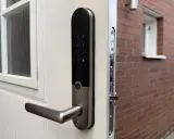 Ett Yale Doorman larmar mitt i natten. Dörren är vit med ett fönster och ett modernt lås.