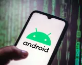 En hand håller en smartphone med Android-logotypen. Bakgrunden visar gröna siffror och symboler, som en kod.