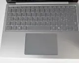 Grå laptop med tangentbord och styrplatta. Tangenterna har svenska tecken, inklusive å, ä, ö. Ett tankstreck syns på tangentbordet.
