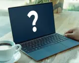 En bärbar dator med ett stort frågetecken på skärmen, bredvid en kaffekopp. Kanske letar du efter ett operativsystem gratis?