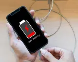 En person försöker ladda sin mobil, men den laddar inte. Batteriikonen visar låg nivå.