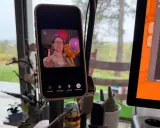 En kvinna gör V-tecken framför ballonger på en iPhone, redo för ett gruppsamtal.