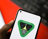 En hand håller en telefon med Android 15-logotypen, en raket som skjuter upp mot stjärnorna.