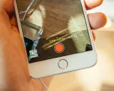 En hand håller en iPhone med inspelningsläget TIME-LAPSE aktivt. En röd inspelningsknapp syns på skärmen.