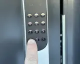 En finger trycker på nollan på en Yale Doorman V2N med wifi.