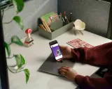 Person håller en iPhone med webbsida som visar en telefon, kanske för att jämföra aviseringar.