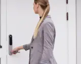 Kvinna med hästsvans öppnar en vit, gammal dörr med en Yale Doorman.