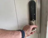 Hand griper handtaget på ett Yale v3 dörrlås med digital knappsats.