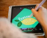 En person använder en penna för att rita en citron och texten "Cemone" i Procreate svenska på en surfplatta.