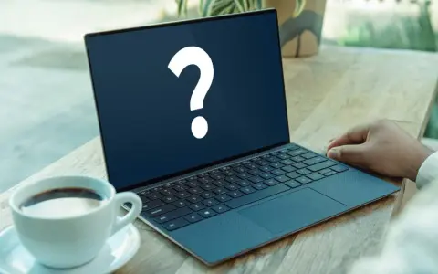 En bärbar dator med ett stort frågetecken på skärmen, bredvid en kaffekopp. Kanske letar du efter ett operativsystem gratis?