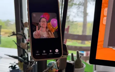 En kvinna gör V-tecken framför ballonger på en iPhone, redo för ett gruppsamtal.