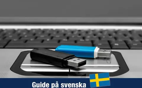 Två USB-minnen, ett svart och ett blått, ligger på ett tangentbord. En guide för Windows 11 USB på svenska.