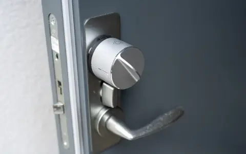 Detaljbild av en silverfärgad Verisure smart låsmodul installerad på en grå dörr.