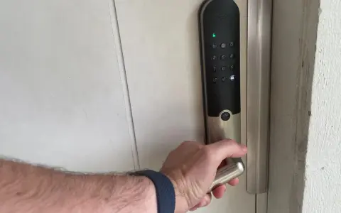 Hand griper handtaget på ett Yale v3 dörrlås med digital knappsats.