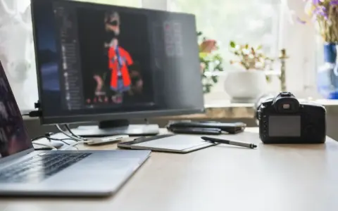 Arbetsplats med laptop, skärm som visar bildredigering, kamera och ritplatta.jpg