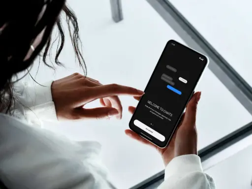 En person håller en mobiltelefon där det står "WELCOME TO CHATS". Appen hjälper dig att skapa grupp sms och hålla dina meddelanden organiserade.