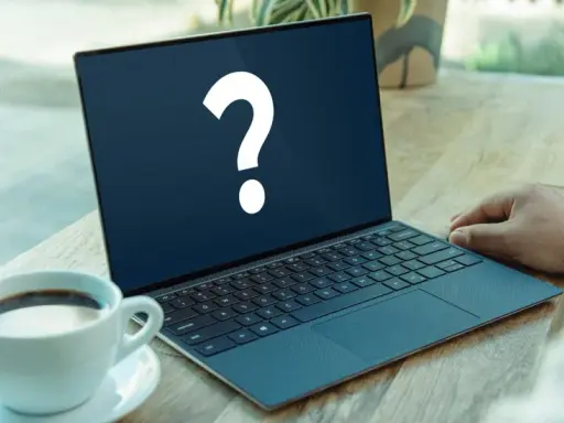 En bärbar dator med ett stort frågetecken på skärmen, bredvid en kaffekopp. Kanske letar du efter ett operativsystem gratis?