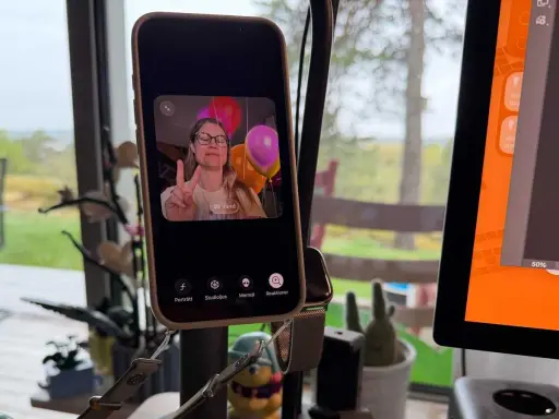 En kvinna gör V-tecken framför ballonger på en iPhone, redo för ett gruppsamtal.