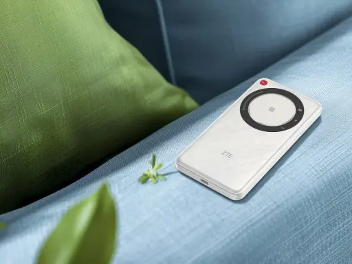 Vit ZTE U30 Air 5G portabel Wi-Fi-hotspot ligger på en blå soffa, bredvid en grön kudde.