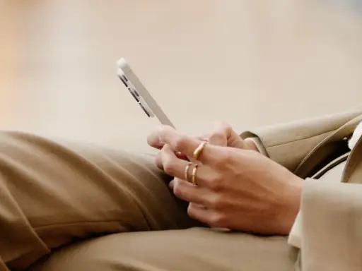 Person med ringar på fingrarna håller en mobiltelefon, kanske för att kolla sitt imei nummer.