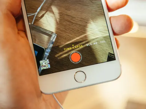 En hand håller en iPhone med inspelningsläget TIME-LAPSE aktivt. En röd inspelningsknapp syns på skärmen.