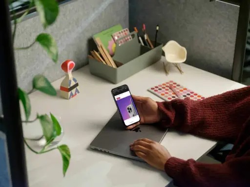Person håller en iPhone med webbsida som visar en telefon, kanske för att jämföra aviseringar.