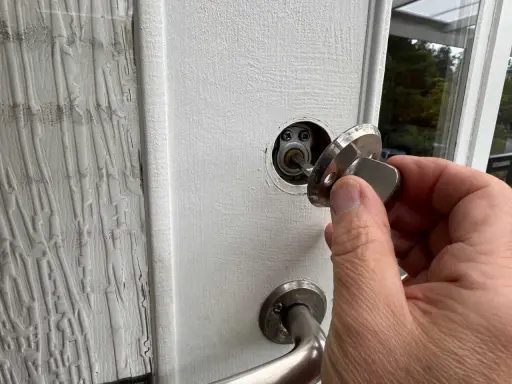 En hand håller en nyckel till en vit dörr, redo att aktivera den smarta låsmodulen.