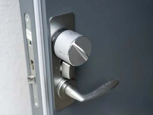 Detaljbild av en silverfärgad Verisure smart låsmodul installerad på en grå dörr.