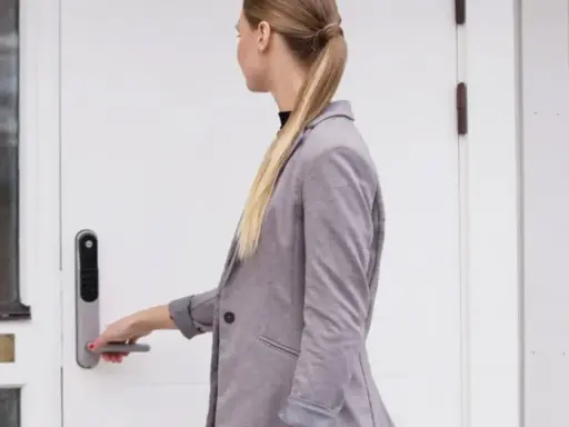 Kvinna med hästsvans öppnar en vit, gammal dörr med en Yale Doorman.