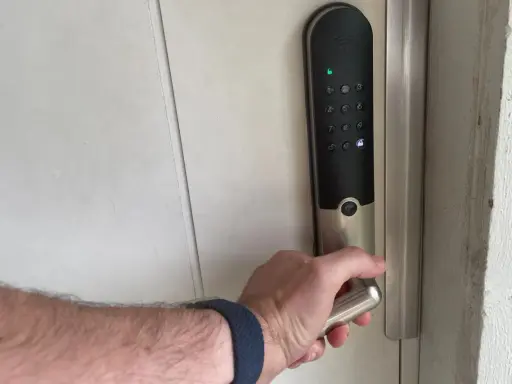 Hand griper handtaget på ett Yale v3 dörrlås med digital knappsats.