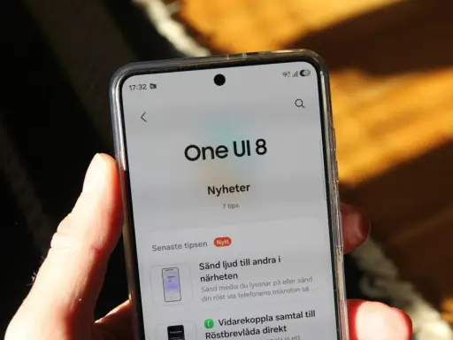 En hand håller en telefon som visar "One UI 8 Nyheter" med tips om funktioner.