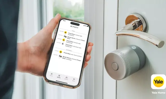 En hand håller en telefon med en Yale Doorman Bluetooth-app som visar aktivitetslogg. Dörren har ett modernt Yale-lås.