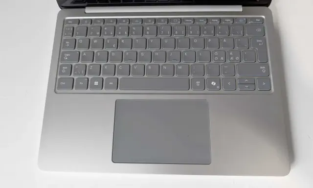 Grå laptop med tangentbord och styrplatta. Tangenterna har svenska tecken, inklusive å, ä, ö. Ett tankstreck syns på tangentbordet.
