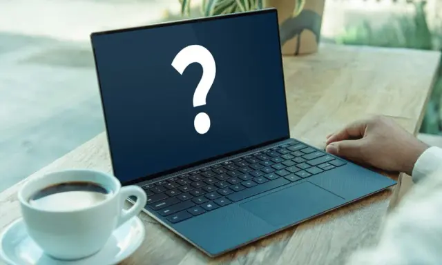 En bärbar dator med ett stort frågetecken på skärmen, bredvid en kaffekopp. Kanske letar du efter ett operativsystem gratis?