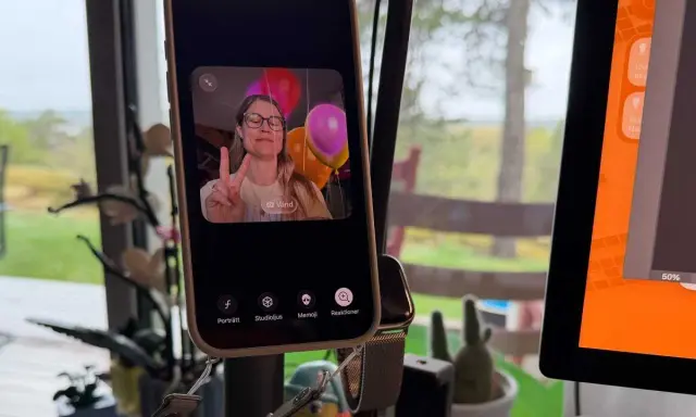 En kvinna gör V-tecken framför ballonger på en iPhone, redo för ett gruppsamtal.