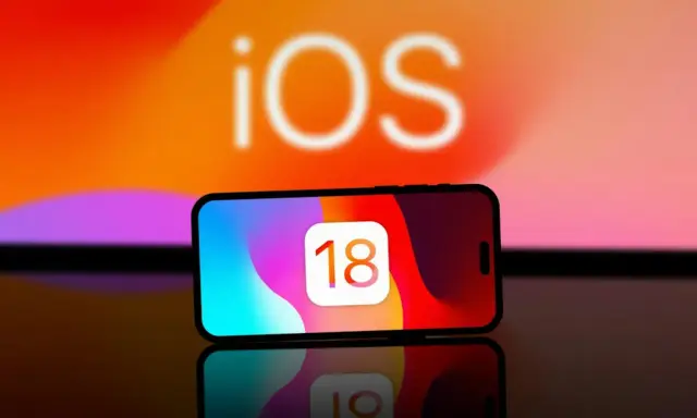 iPhone med iOS 18-ikonen. Kanske dags att byta namn på iPhone för att spegla den nya versionen?