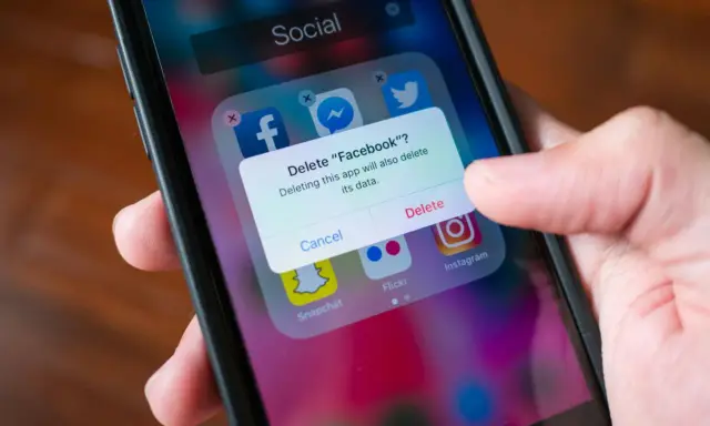 En finger trycker på "Delete" på en iPhone. En ruta frågar om man vill radera Facebook och dess data. Detta är inte hur man uppdaterar en app.