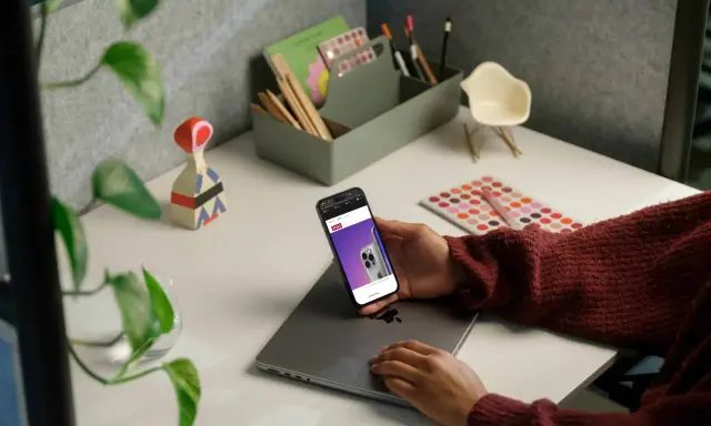 Person håller en iPhone med webbsida som visar en telefon, kanske för att jämföra aviseringar.
